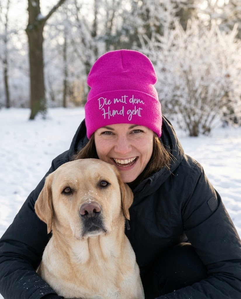 Frau mit Hund trägt die pinke Mütze Die mit dem Hund geht im Winter