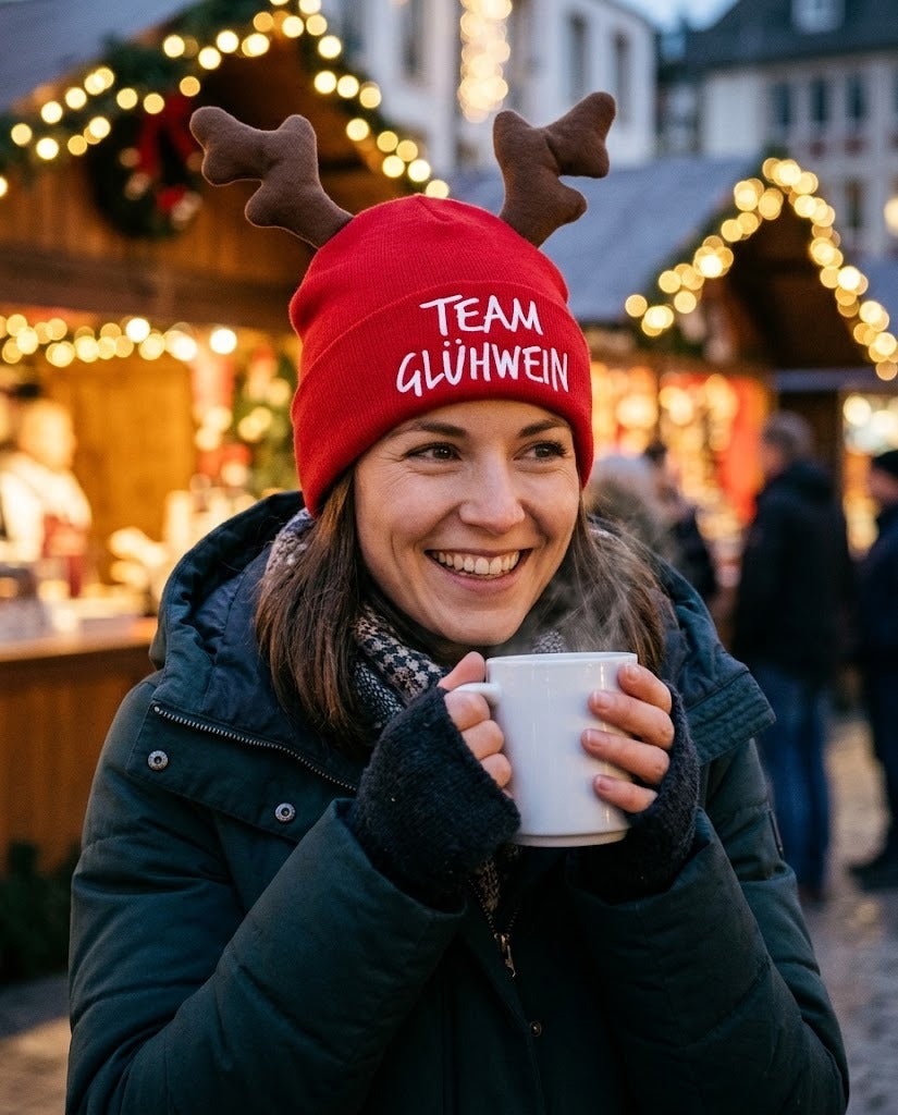 Frau trägt die rote Elchmütze Team Glühwein auf dem Weihnachtsmarkt